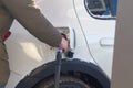 To fill up the car with gasoline at the gas station, a man pours gasoline into the tank of a white car in winter