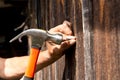 To hammer a nail with a hammer. Older worker carpenter