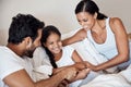 To hear her laugh is music to their hearts. parents tickling their little daughter while lying in bed together at home. Royalty Free Stock Photo