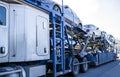 White big rig car hauler long distance semi truck transporting cars on two level semi trailer on the straight road Royalty Free Stock Photo