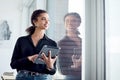 To reach the top, you have to work smarter. a young businesswoman looking through a window while using a digital tablet