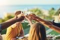 To us growing closer and stronger together. a group of friends raising up their glasses for a toast while sitting around Royalty Free Stock Photo