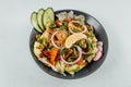 To view closeup of roasted orange bell peppers, onion, radish, lemon and lettuce in a black bowl