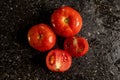 To view of fresh ripe tomatoes with water droplets on a black granite kitchen counter surface Royalty Free Stock Photo