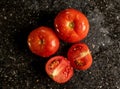 To view of fresh ripe tomatoes with water droplets on a black granite kitchen counter surface Royalty Free Stock Photo