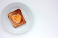 Toast bread with fried egg in a heart shaped hole on plate on white background. Creative Valentine\'s day