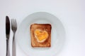 Toast bread with fried egg in a heart shaped hole on plate on white background. Creative Valentine\'s day