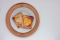 Toast bread with fried egg in a heart shaped hole on plate on white background. Creative Valentine\'s day