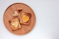 Toast bread with fried egg in a heart shaped hole on wooden board on white background.