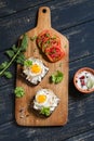 Toast with feta cheese and fried quail egg, fresh tomatoes on a dark wooden surface Royalty Free Stock Photo