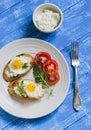 Toast with feta cheese and fried quail egg, fresh tomatoes on a wooden surface Royalty Free Stock Photo