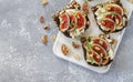 Toast with figs, cheese, honey, herbs and nuts. Delicious breakfast on white board top view