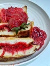 Toast filled with strawberry jam on a round plate