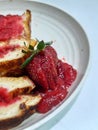 Toast filled with strawberry jam on a round plate