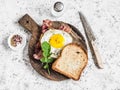 Toast with fried egg, bacon and arugula on the wooden cutting board. Delicious breakfast.