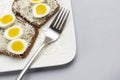 Toast with grated cheese and boiled quail eggs, fork on white plate