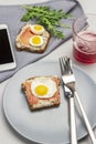 Toast with jamon and boiled quail eggs, fork and knife on gray plate