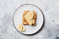 Toast with peanut butter, banana slices, honey and almond flakes on old gray concrete background. Top view Royalty Free Stock Photo