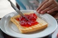 Toast with strawberry jam on white plate and woman hand holding knife Royalty Free Stock Photo