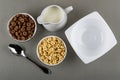 Cereal breakfasts with chocolate and caramel in bowls, pitcher with yogurt, spoon, empty bowl on table. Top view Royalty Free Stock Photo