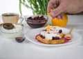 Man sprinkles orange zest toasted French bread with curd cream and plum jam. Royalty Free Stock Photo
