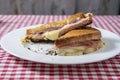 Toasted ham and cheese sandwich on a white plate on a table with a tablecloth Royalty Free Stock Photo