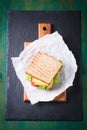 Toasted sandwich with salad leaves, tomatoes and cheese with fork on a cutting board on a dark background Royalty Free Stock Photo