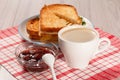 Toasted slices of bread with cheese on white plate, cup of coffee, bowl with strawberry jam and spoon on napkin Royalty Free Stock Photo