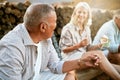 . Toasting marshmallows, camping and adventure with a senior man and his retired friends sitting outside. Holiday Royalty Free Stock Photo