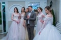 A toastmaster posing for the camera among the bride models