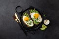 Toasts with avocado, asparagus and fried egg on black plate