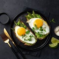 toasts with avocado, asparagus and fried egg on black plate