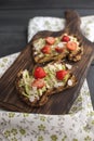 Toasts with avocado and strawberries, on grain bread for breakfast. White napkin with spikes and a black wooden background. Copy