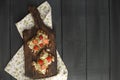 Toasts with avocado and strawberries, on grain bread for breakfast. White napkin with spikes and a black wooden background. Flat