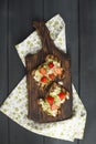 Toasts with avocado and strawberries, on grain bread for breakfast. White napkin with spikes and a black wooden background. Flat