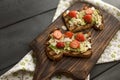 Toasts with avocado and strawberries, on grain bread for breakfast. White napkin with spikes and a black wooden background. copy