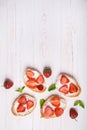 Toasts or bruschetta with strawberries on cream cheese on white wooden background. Royalty Free Stock Photo