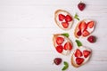 Toasts or bruschetta with strawberries on cream cheese on white wooden background. Royalty Free Stock Photo