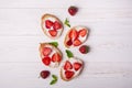 Toasts or bruschetta with strawberries on cream cheese on white wooden background. Royalty Free Stock Photo