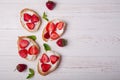 Toasts or bruschetta with strawberries on cream cheese on white wooden background. Royalty Free Stock Photo