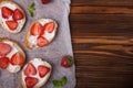 Toasts or bruschetta with strawberries on cream cheese on wooden background. Royalty Free Stock Photo