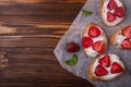 Toasts or bruschetta with strawberries on cream cheese on wooden background. Royalty Free Stock Photo