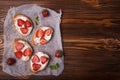 Toasts or bruschetta with strawberries on cream cheese on wooden background. Royalty Free Stock Photo