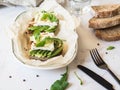 Toasts with camembert cheese, avocado slices, arugula and walnut on oval plate