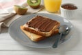 Toasts with choco cream on plate, kiwi and juice on wooden background