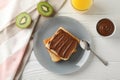 Toasts with choco cream on plate, kiwi and juice on wooden background