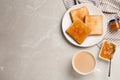 Toasts, orange jam and cup of coffee served on light marble table, flat lay. Space for text Royalty Free Stock Photo