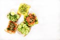 Toasts, sandwiches with cucumbers, tomatoes, eggs, sprouts, herbs and nuts on a plate on a white background. Vegetarian food Royalty Free Stock Photo