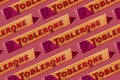 Toblerone Swiss chocolate bar with nuts. New package with mountain logo on pink background. Candy sweets are a classic