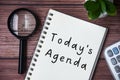 Today's agenda text on notepad. Magnifying glass and calculator background. Royalty Free Stock Photo